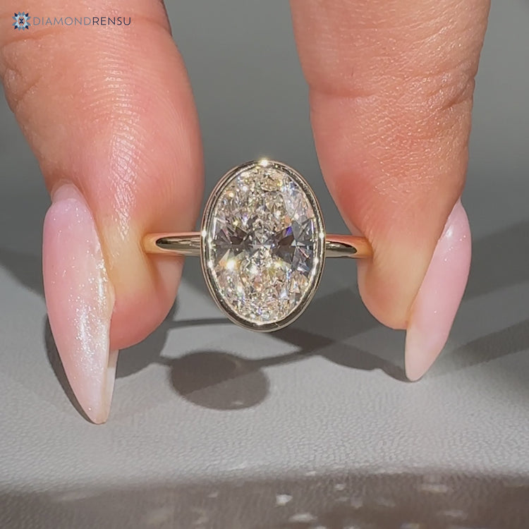 Oval diamond solitaire ring with bezel setting.
