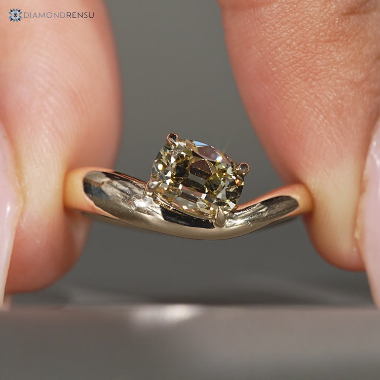 Cushion cut diamond solitaire ring with four claw prongs.
