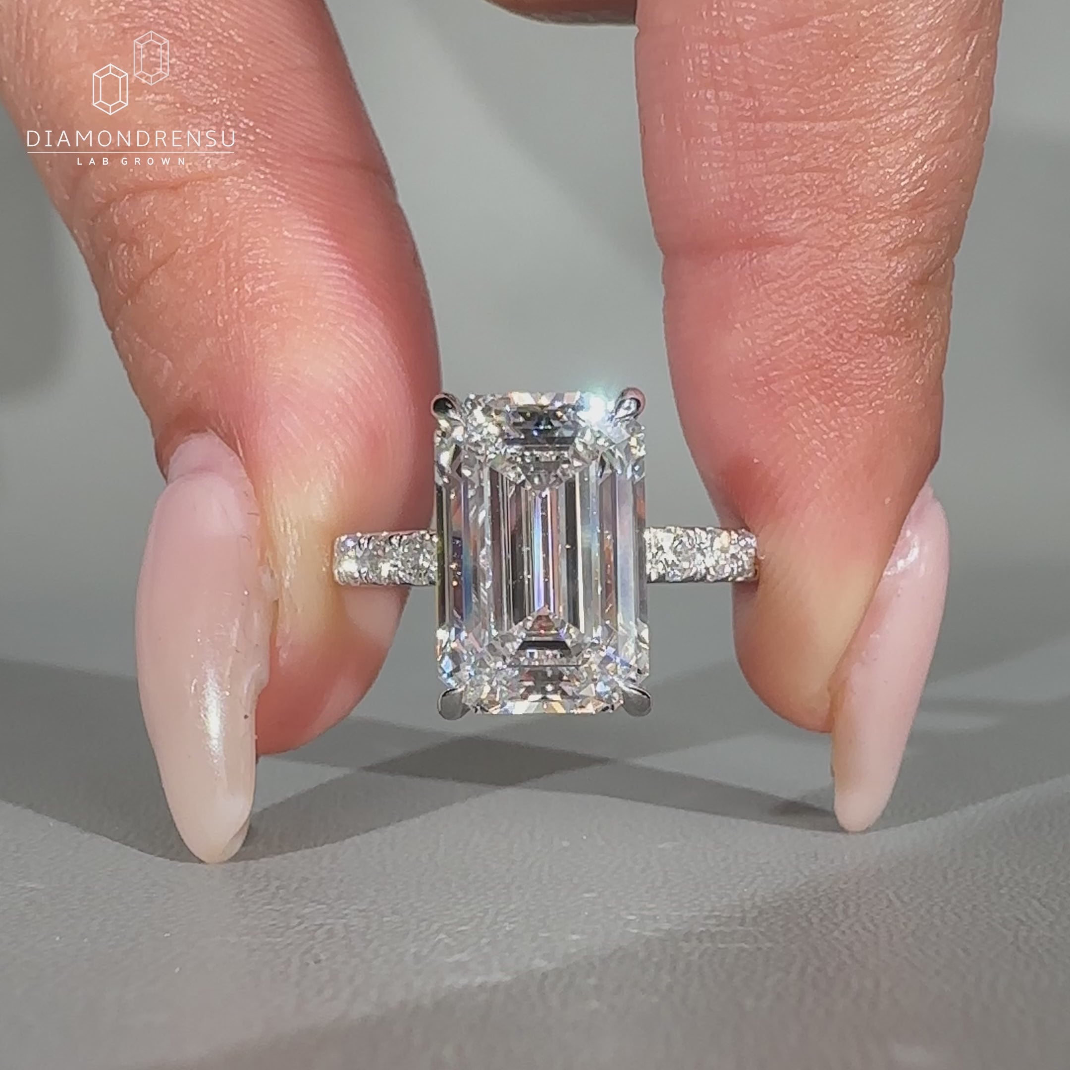 Emerald cut diamond ring featuring pave round diamonds.