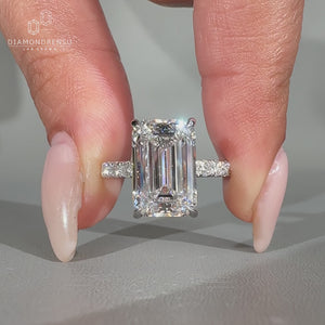 Emerald cut diamond ring featuring pave round diamonds.