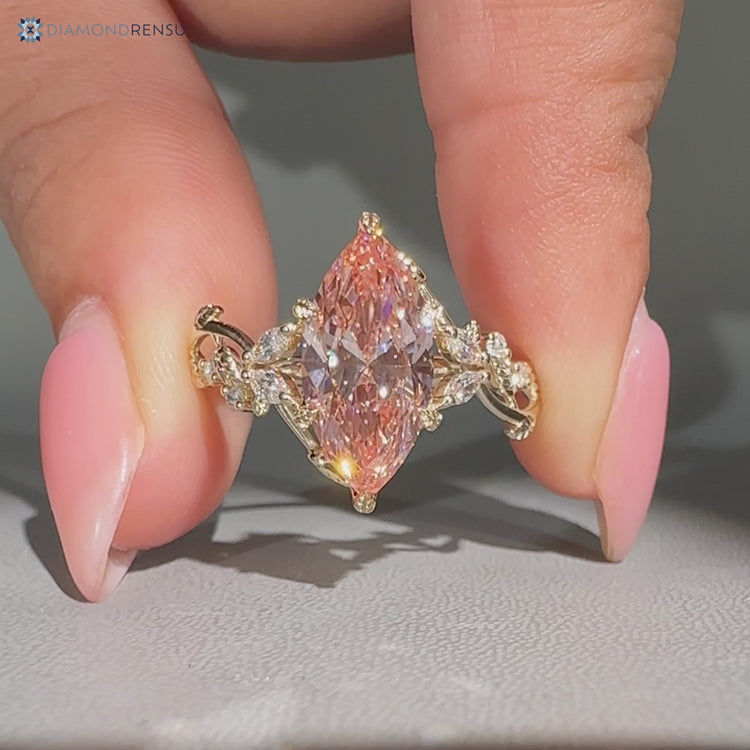 Pink diamond ring with round and marquise side stones.