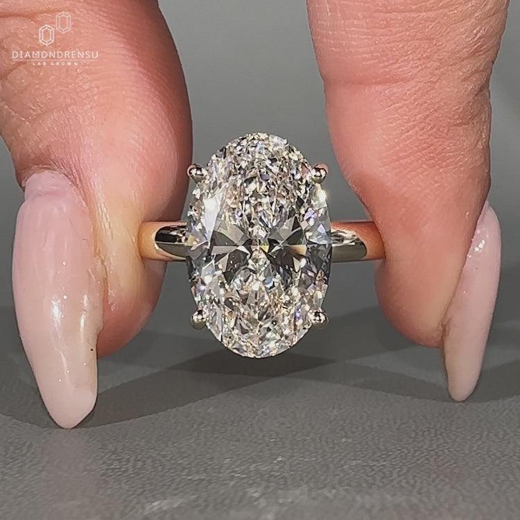 Oval hidden halo engagement ring with round diamond detail.