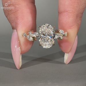 Oval diamond ring with marquise side stones and hidden halo in yellow gold.
