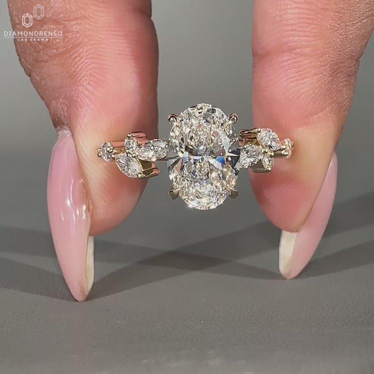 Oval diamond ring with marquise side stones and hidden halo in yellow gold.
