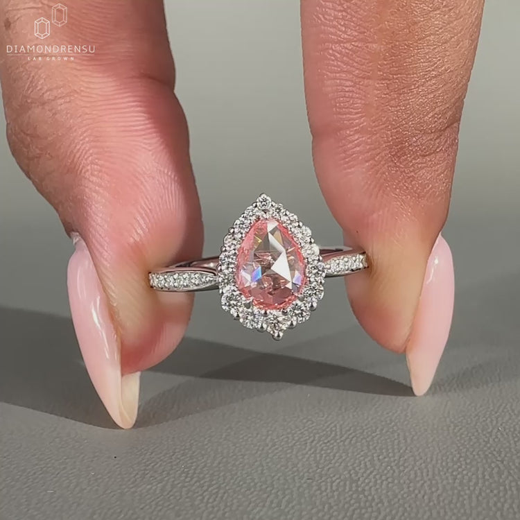 Pear diamond ring with round diamond halo and pavé setting.

