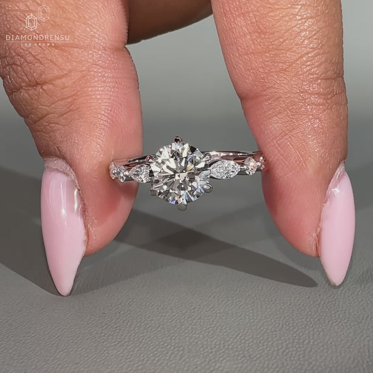 Marquise and round diamond ring featuring a unique side stone engagement design.
