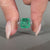 Asscher cut emerald ring hidden halo round diamond set.

