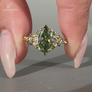 Marquise diamond ring green emerald side gemstone.