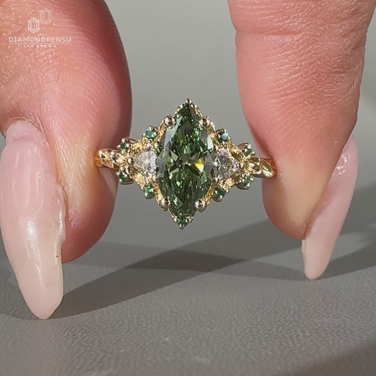 Marquise diamond ring green emerald side gemstone.