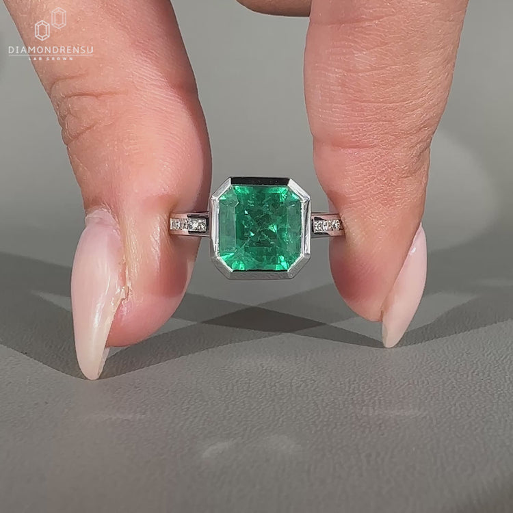 Asscher gemstone ring emerald bezel round diamond band.
