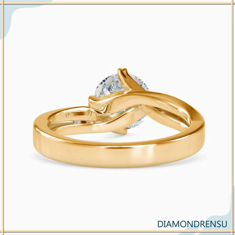 Twisted solitaire engagement ring featuring a round cut diamond in a modern design.